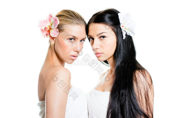 两个美丽的年轻黑发女人拥有完美的皮肤，<strong>蓝色</strong>的眼睛和<strong>奢华</strong>的珠宝耳环，手持百合花和看着相机