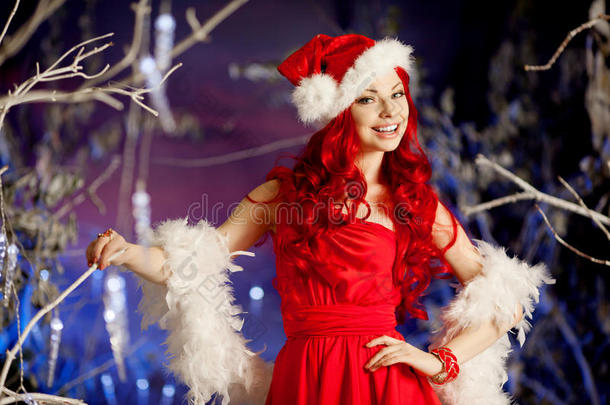 圣诞树旁的年轻美女微笑的圣诞老人。时尚奢华女孩庆祝新年。美丽奢华时尚