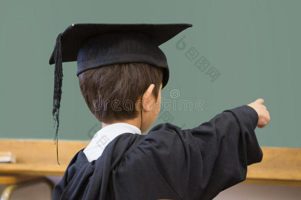 穿着毕业袍的可爱小学生指着教室