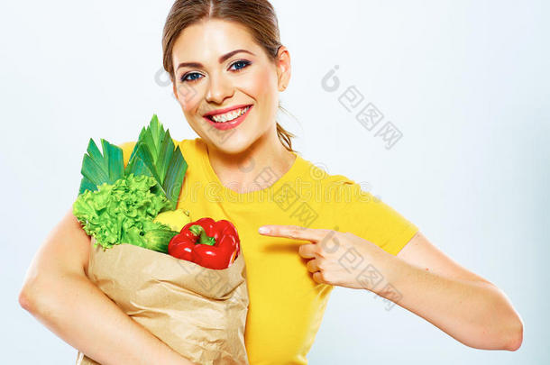 拿着绿色食品的女人用手指着农产品