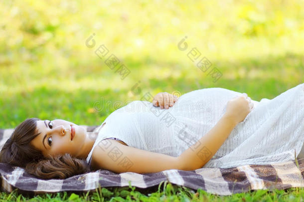 可爱的孕妇躺在草地上