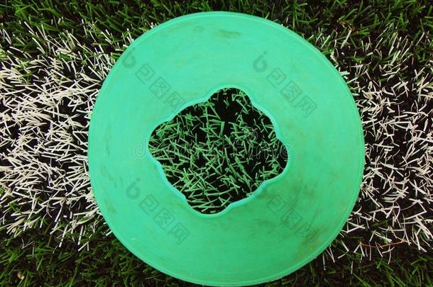 漆成白色线条的亮绿色蓝色塑料圆锥体。塑料足球场绿色草坪磨砂黑橡胶操场