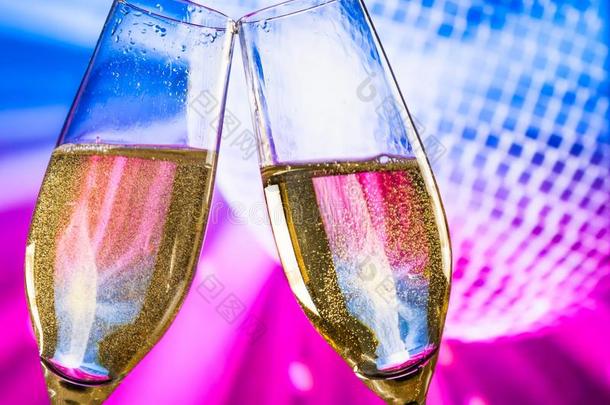 带有金色泡泡的香槟长笛在闪闪发光的蓝色和紫色迪斯科球背景上发出欢呼声