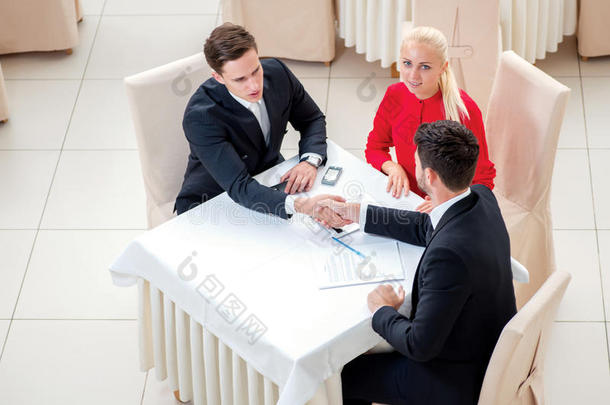 签署合同。三位成功自信的商人握手。穿着正装的商人坐在