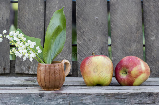 红苹果和<strong>铃</strong>兰花在一个木质背景的陶瓷小杯子里