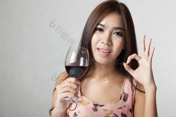 美丽的亚洲女人<strong>展示</strong>OK标志，拿着一杯<strong>红酒</strong>