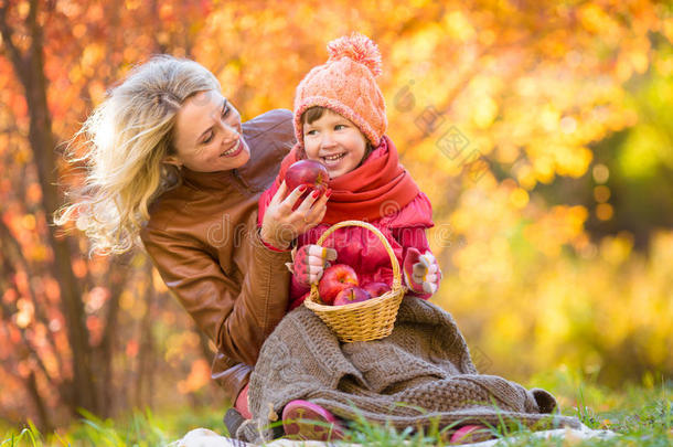 妈妈和孩子在秋天公园一起吃松果