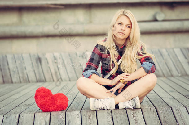 悲伤孤独的女孩坐在木板上靠近一颗<strong>大红</strong>色的心
