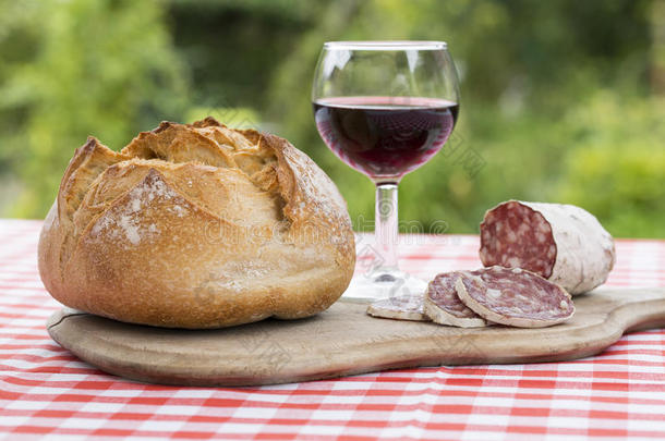 花园里有面包和红酒的木板上的法国香肠