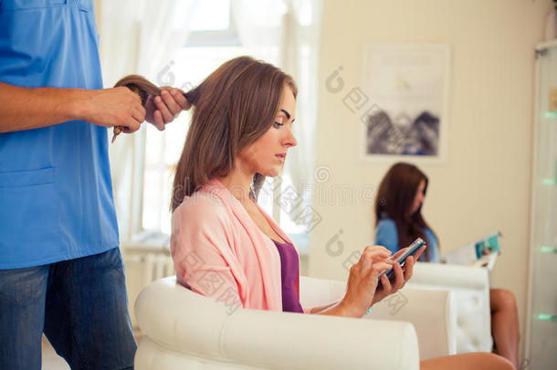 <strong>美发</strong>师用手机为女理发师梳头