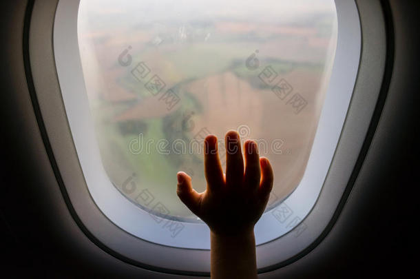 手放在模糊背景下有风景的飞机窗户上