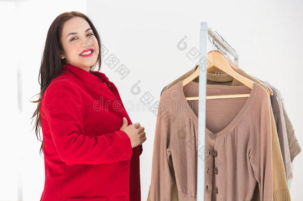 浅褐色微笑的女人试着穿红外套