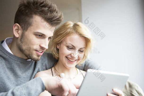 快乐的年轻夫妇在咖啡厅使用数字平板电脑