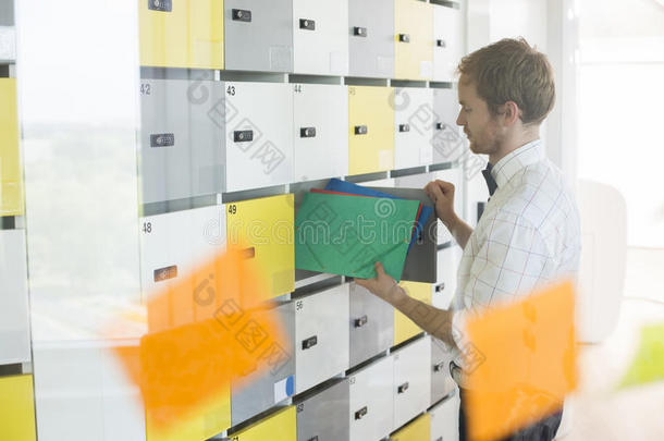 商人将文件放入创意办公室储物柜的侧视图
