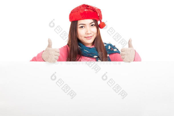 戴着红色圣诞帽的亚洲女孩在空白的牌子后面竖起大拇指