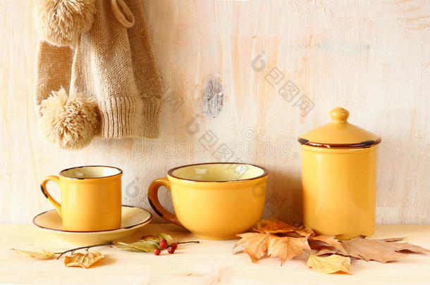 一套复古咖啡杯和罐子放在质感古朴的木桌和秋叶上。图像经过回复过滤。