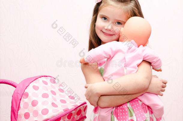可爱的微笑小女孩玩她的玩具马车和洋娃娃