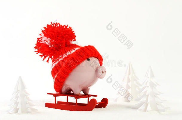 带着红帽子的小猪盒站在雪地上的红色雪橇上，周围是积雪覆盖的树——雪橇车