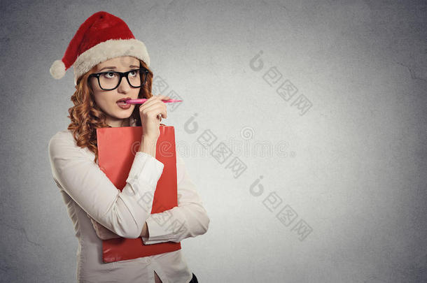 戴着圣诞帽的女人在摄影棚摆姿势，想着礼物的<strong>点子</strong>