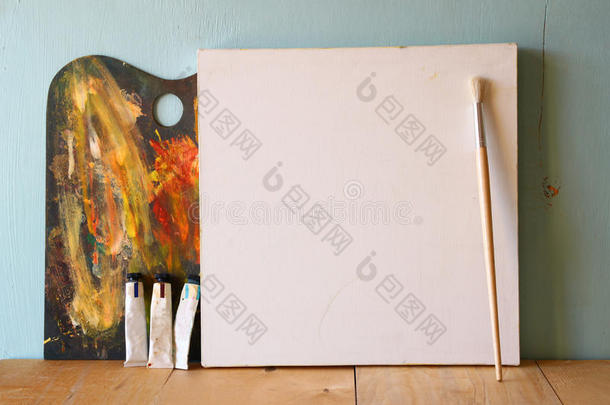 空白帆布或海报，木制桌子和纹理背景上的木制调色板