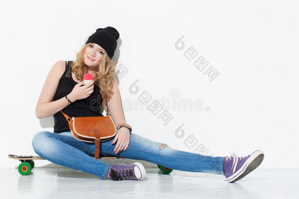 年轻漂亮开朗的时尚女孩，穿着牛仔裤、运动鞋、帽子，肩上背着一个古董包坐在长木板上吃饭