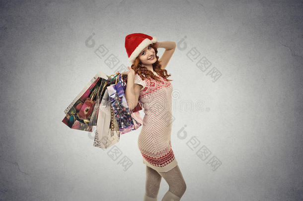 戴着红色圣诞老人帽的女人，带着圣诞礼物，购物袋