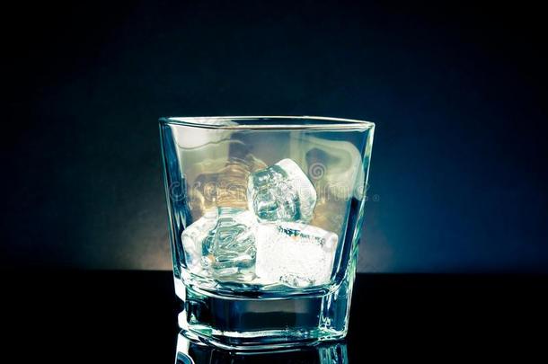空威士忌玻璃与冰和淡色蓝色迪斯科在黑色背景