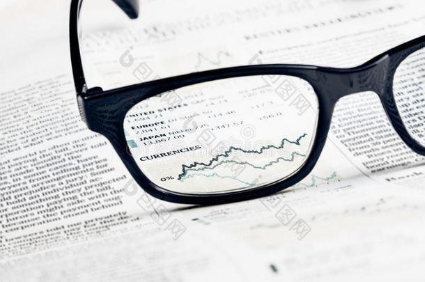 金融图表和图表货币通过金融报纸上的眼镜镜头看到