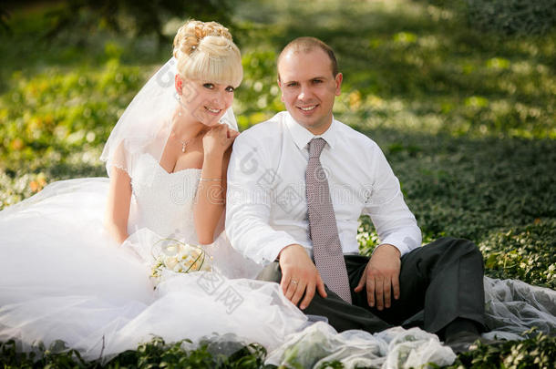 新郎新娘拥抱坐在绿草丛中