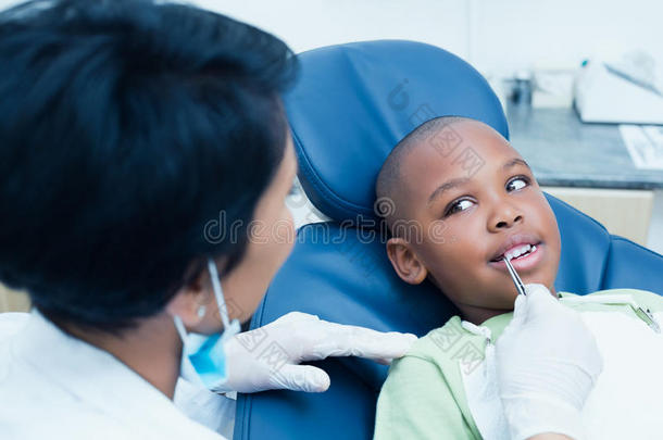 牙医在牙医椅子上检查男孩的牙齿