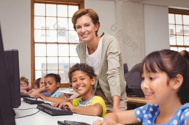 计算机班可爱的小学生，老师对着相机微笑