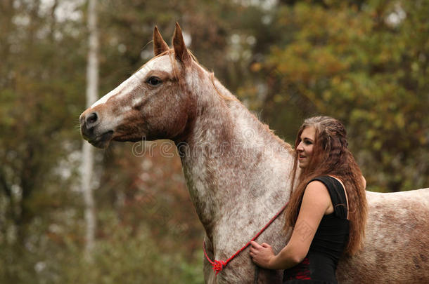漂亮的女孩，穿着漂亮的衣服，站在漂亮的马旁边