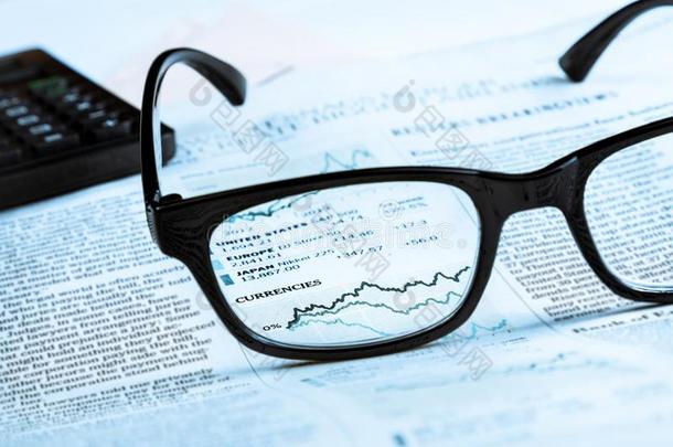 金融图表和图表货币通过金融报纸上的眼镜镜头看到
