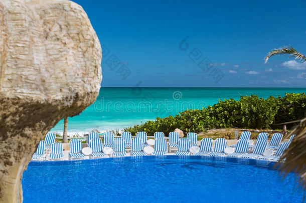 华丽，迷人的热带游泳池，在蔚蓝的绿松石海洋和蓝天背景下