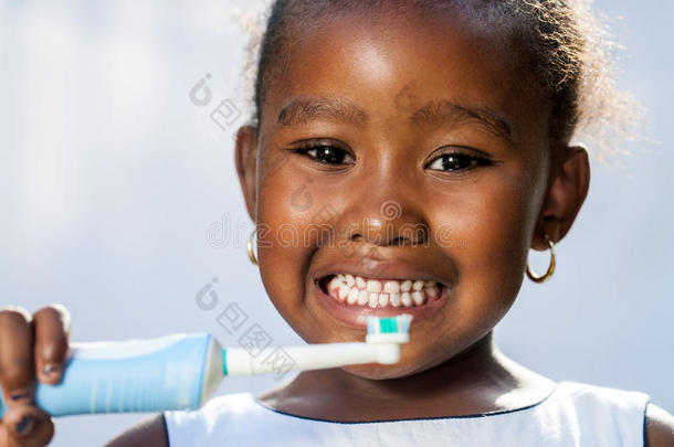 可爱的小阿弗罗女孩拿着电动牙刷。