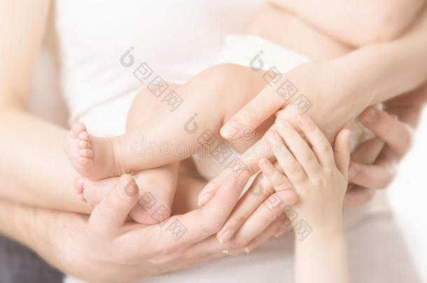 家庭手和婴儿新出生的脚，母亲父亲的手臂，孩子的身体拥抱新生的孩子的脚