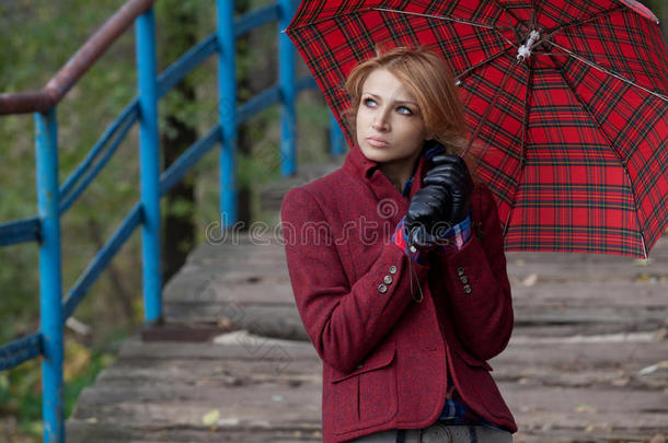 漂亮的金发女人在红色雨伞<strong>下摆</strong>姿势