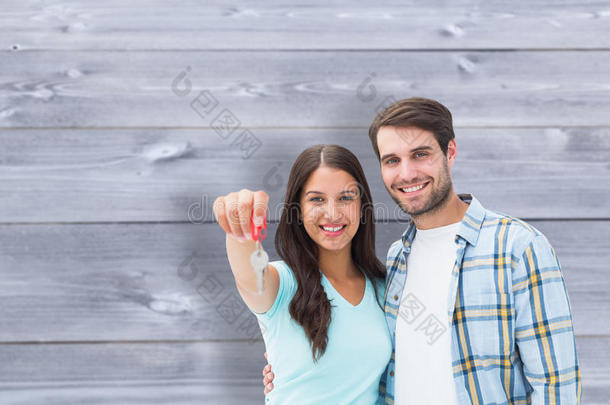 <strong>喜气</strong>洋洋的年轻夫妇展示新房子钥匙的合成图片
