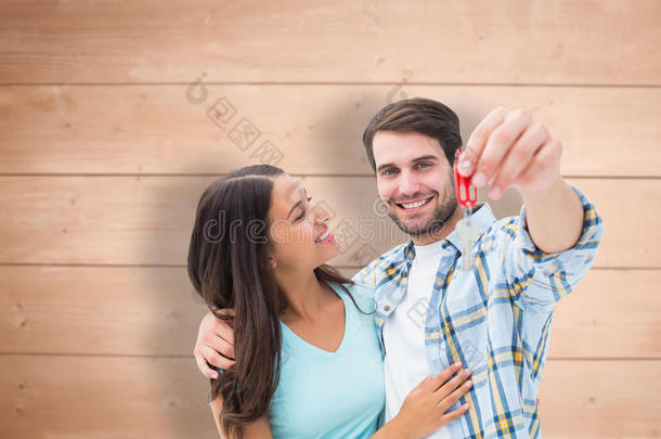 喜气洋洋的年轻夫妇展示新房子钥匙的合成图片