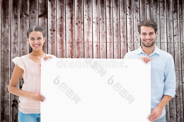 有吸引力的年轻夫妇微笑着拿着<strong>海报</strong>的复合图像