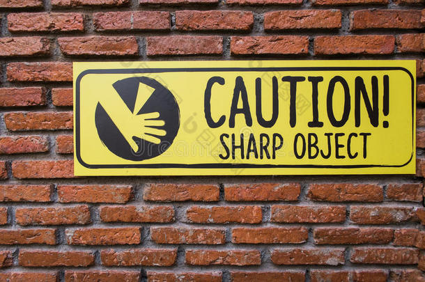 砖墙上的警告标志，小心锋利的物体