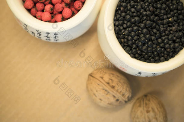 瓷杯和坚果中的黑色扁豆和红色浆果