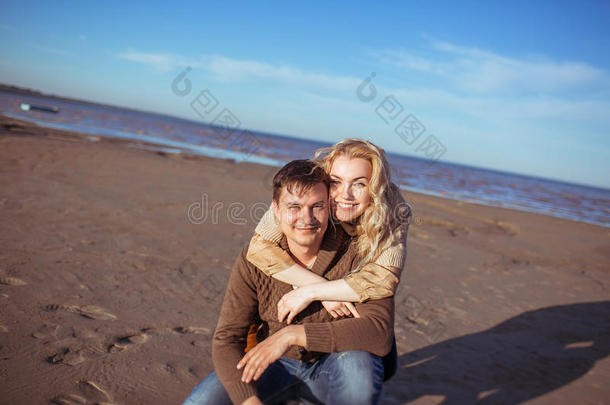 一个男人<strong>坐</strong>在沙滩上，一个女人<strong>拥</strong>抱着他