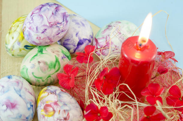 十几个手工色的复活节彩蛋和一支燃烧的蜡烛