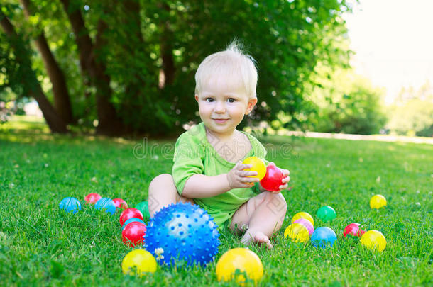 可爱的小男孩坐在草地上玩球