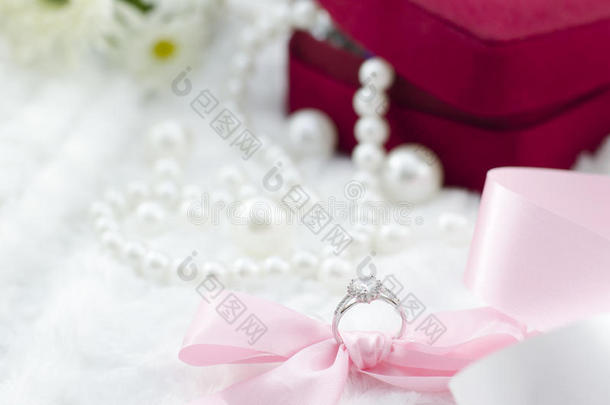 珍珠项链背景上的<strong>钻石戒指</strong>和粉红色丝带