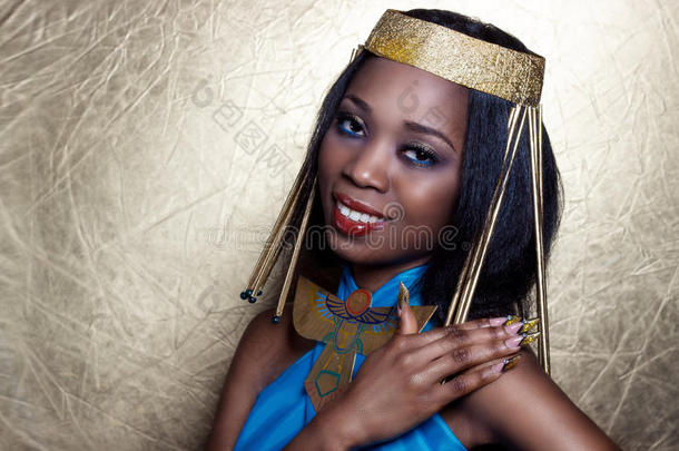 美丽的深色皮肤的女孩，黑色的女人，在埃及女王的形象中，红色的嘴唇，明亮的妆容，展示了长长的指甲
