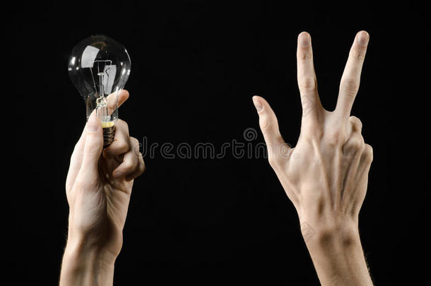 能源消耗和节能主题：人手拿灯泡在黑色背景在工作室