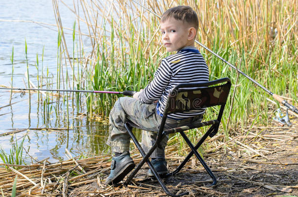 男孩坐在椅子上，在<strong>芦苇丛</strong>中钓鱼
