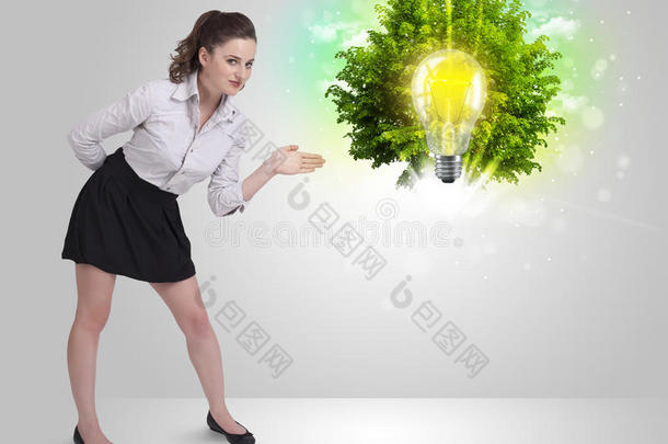 年轻女孩用绿树展示创意灯泡